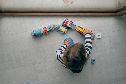 Girl plays with wooden train toy for article how to make your toys last