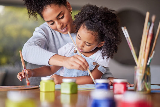 child painting with childrens paint set while mom helps