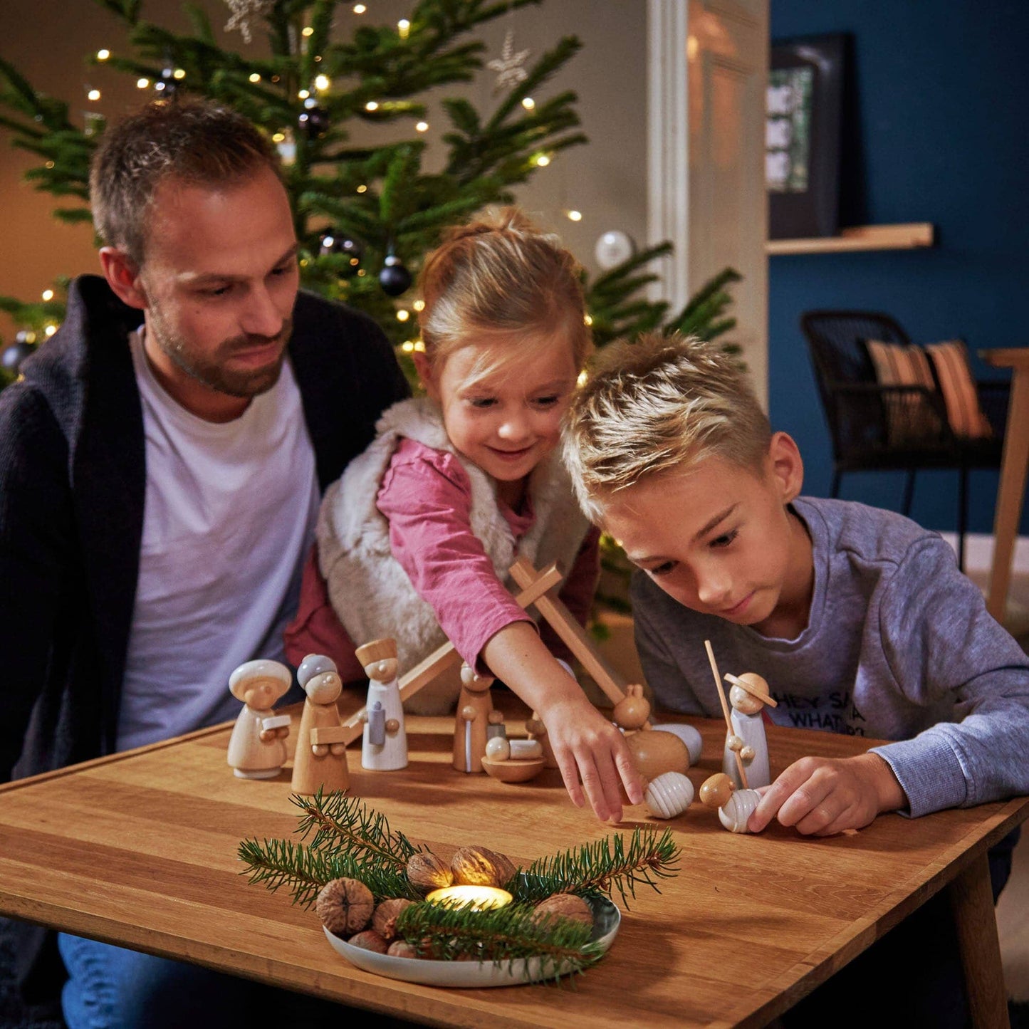 Family arranges Childs wood nativity set in scene