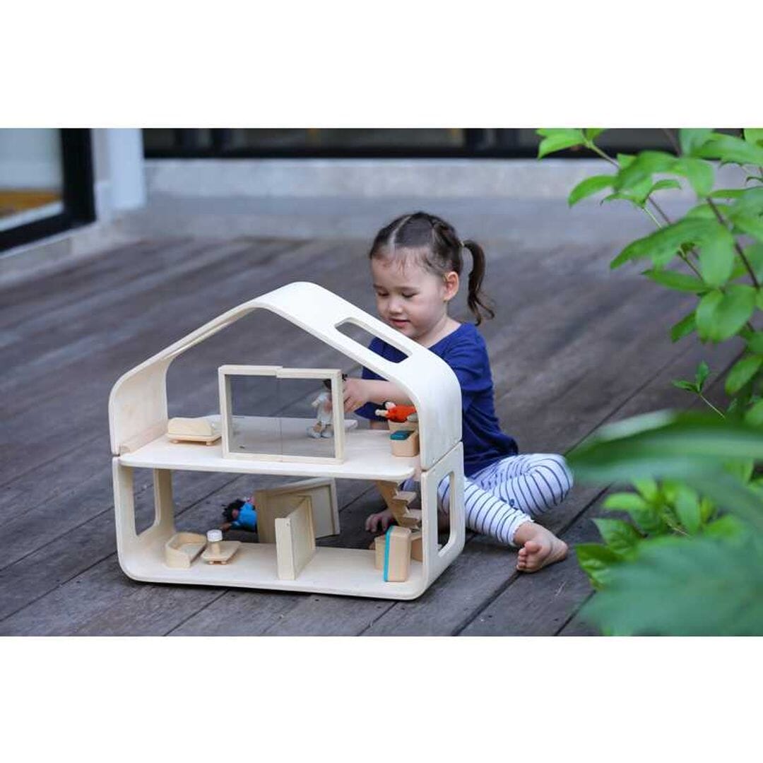 Child plays outside with Mid century modern dollhouse with furniture