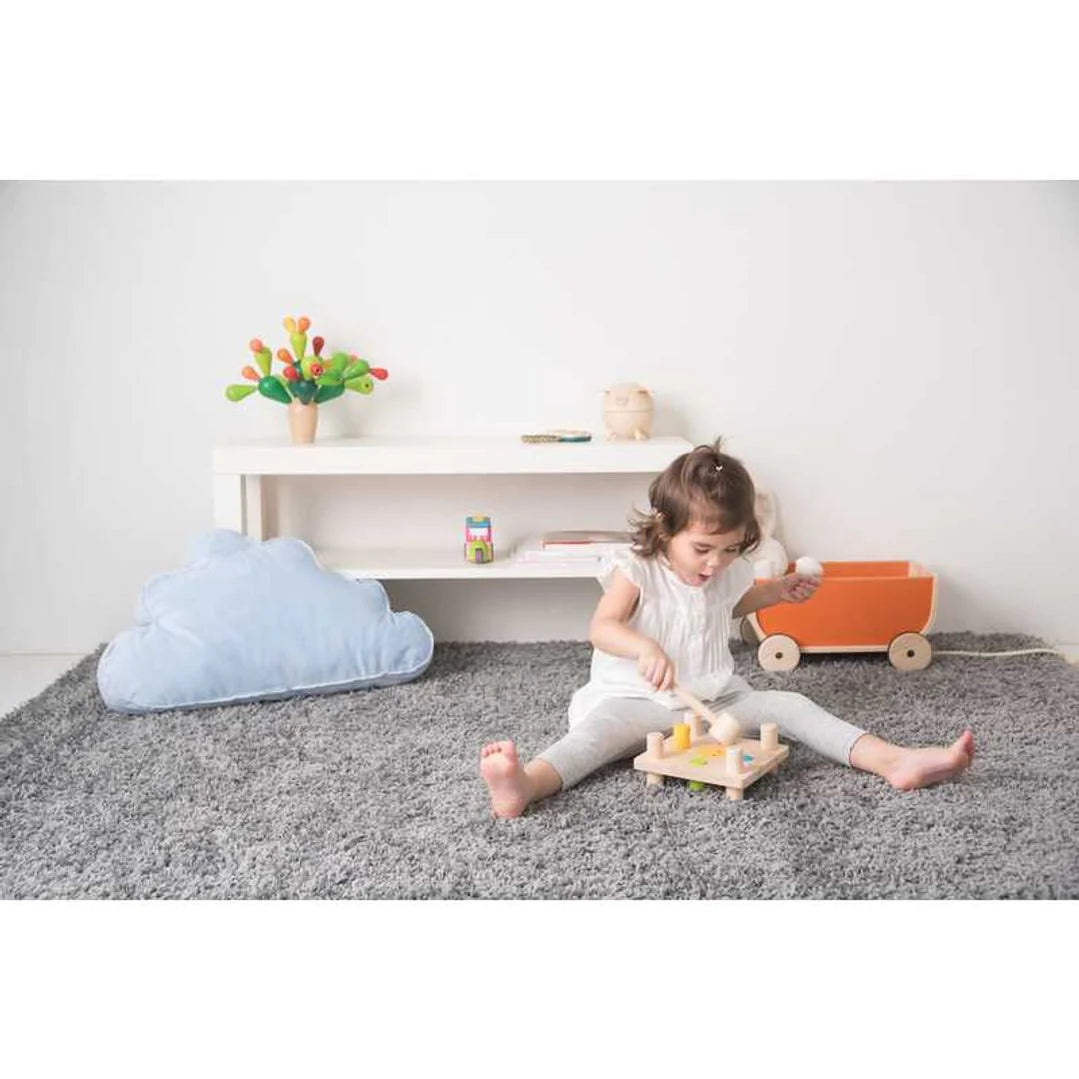 Girl plays with PlanToys Hammer Peg wooden peg and hammer toy, pounds colorful pegs with wooden mallet