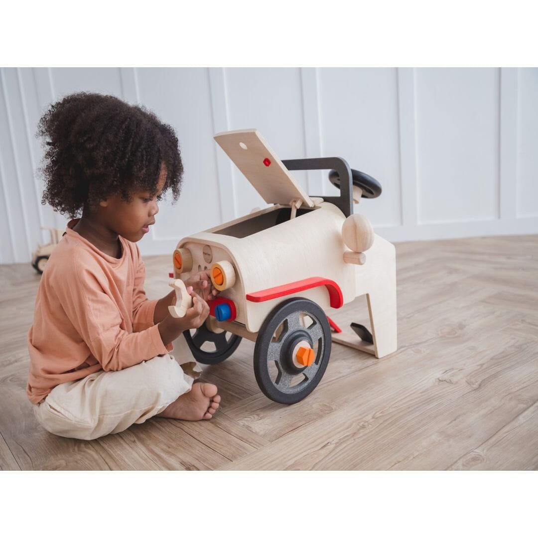 Child plays with wrench from PlanToys Motor Mechanic car for 3 year olds and up