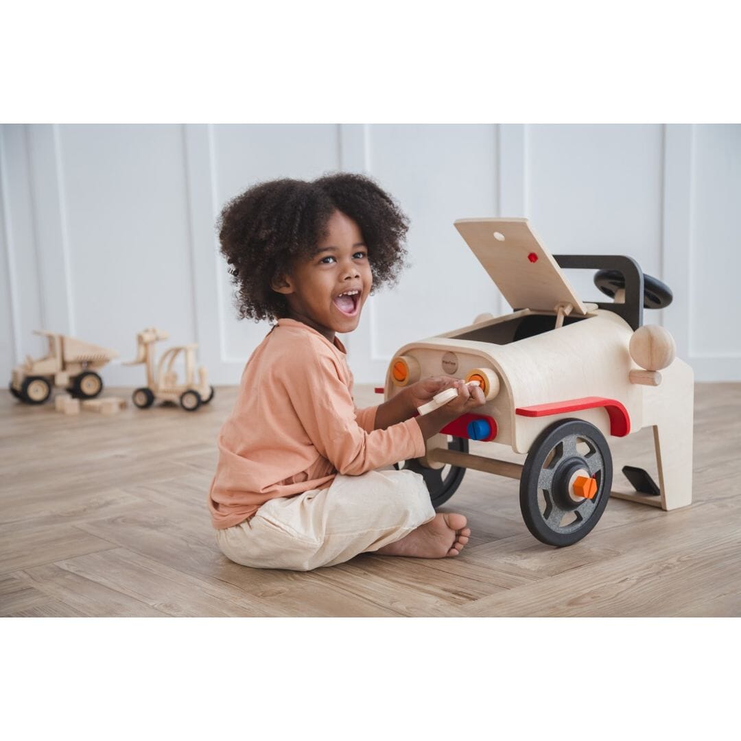Happy child playing with PlanToys Motor Mechanic car for 3 year olds and up
