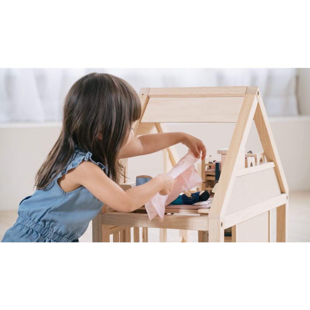 Child plays with My First Dollhouse by PlanToys with open top view and natural unfinished wood.