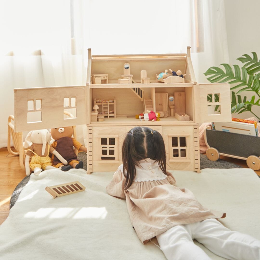 Victorian dollhouse inside with child playing in front.