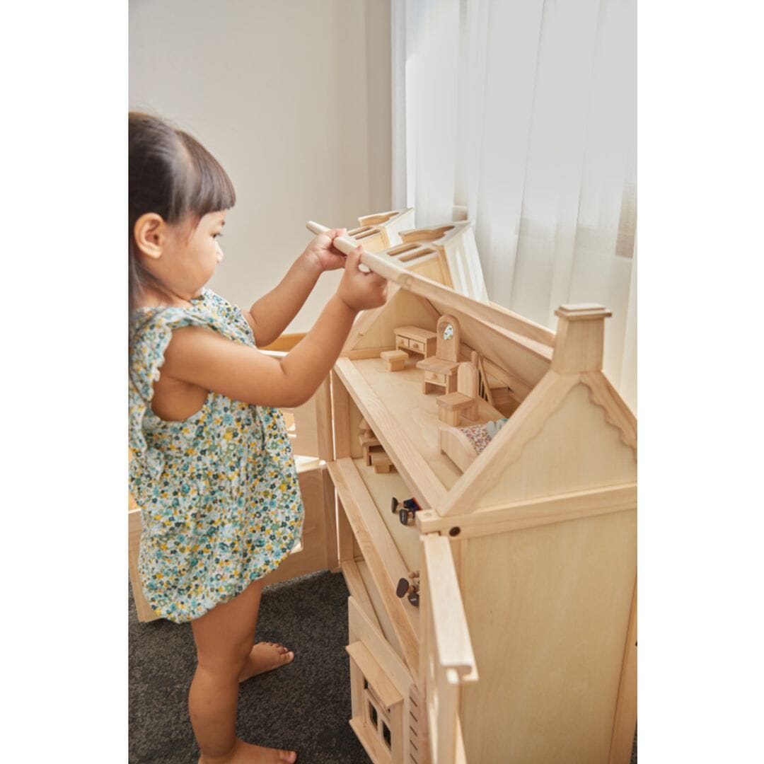 Child opens attic on large victorian dollhouse.
