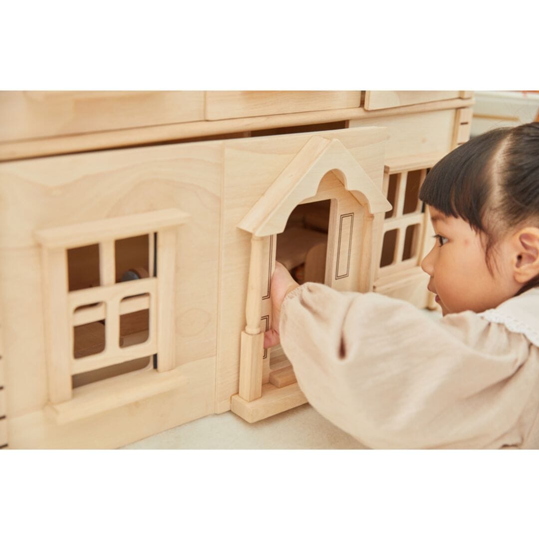 Child peeks inside a large Victorian dollhouse.