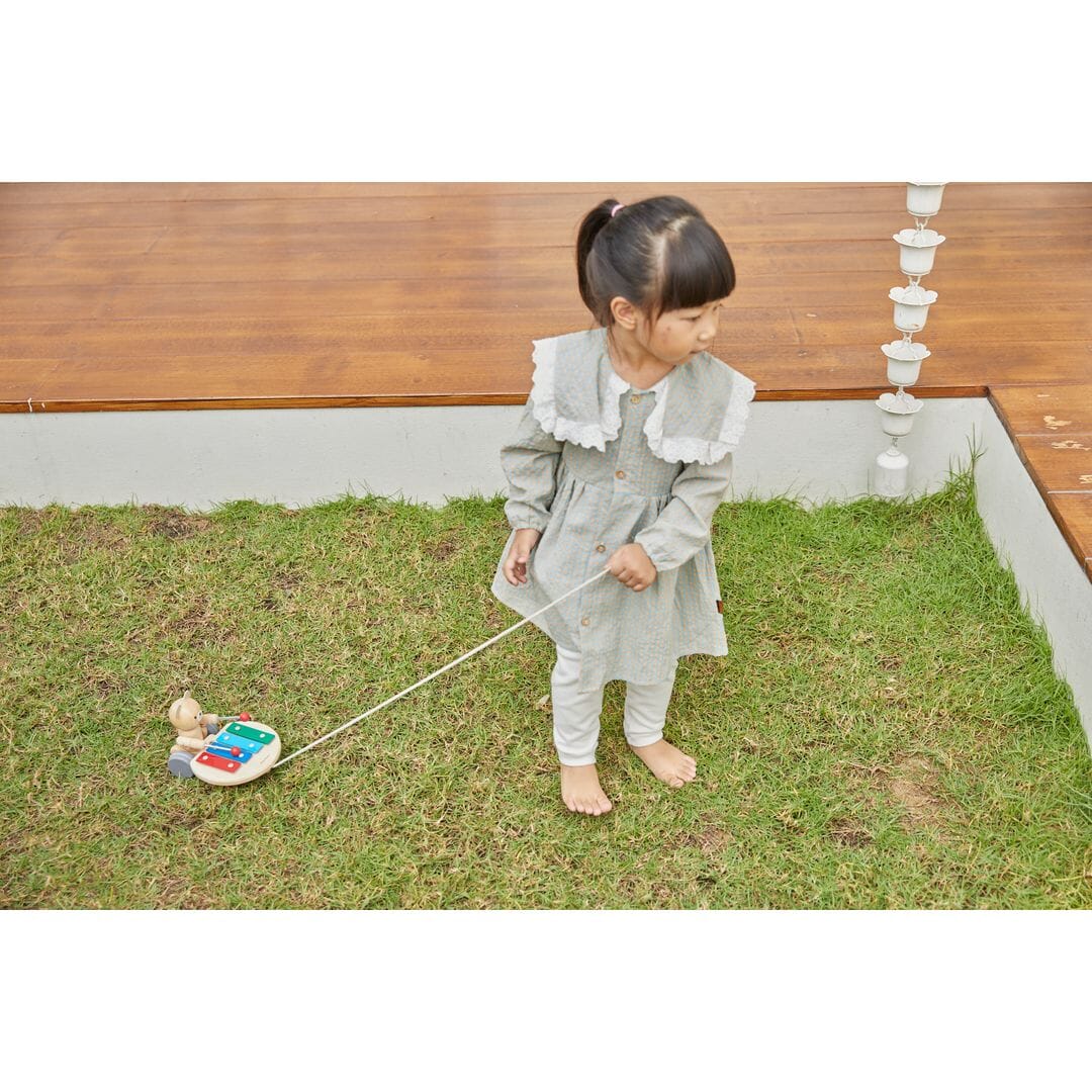 Girls toddler outside with PlanToys Pull Along Musical Bear