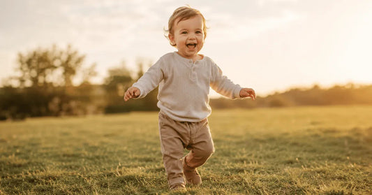Toddler around 18 months walking confidently on grass with arms out for balance