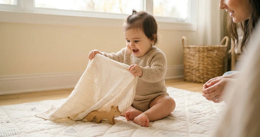 Baby lifting a cloth to discover a hidden toy, showing delighted surprise during a peekaboo game