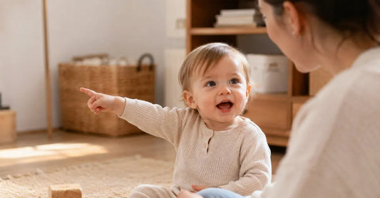 Toddler around 15 months pointing excitedly while looking at a parent, mouth open mid-word