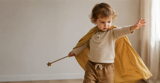 Toddler in colorful dress-up costume, deeply absorbed in pretend play with focused expression