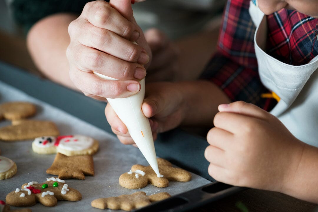 mom baking holiday treats gingerbread cookies with child