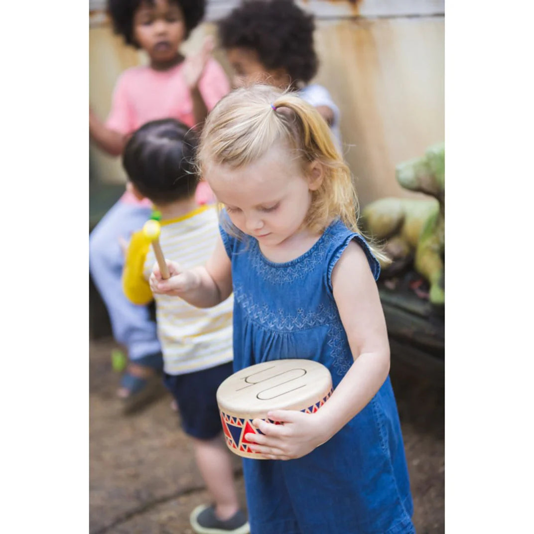 Little girl plays Toy Wooden Drum from PlanToys made from solid wood