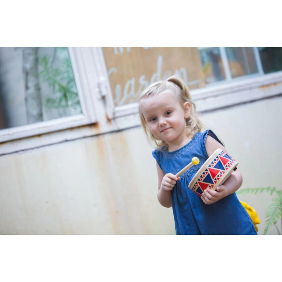 Girl in blue plays a Toy Wooden Drum from PlanToys made from solid wood