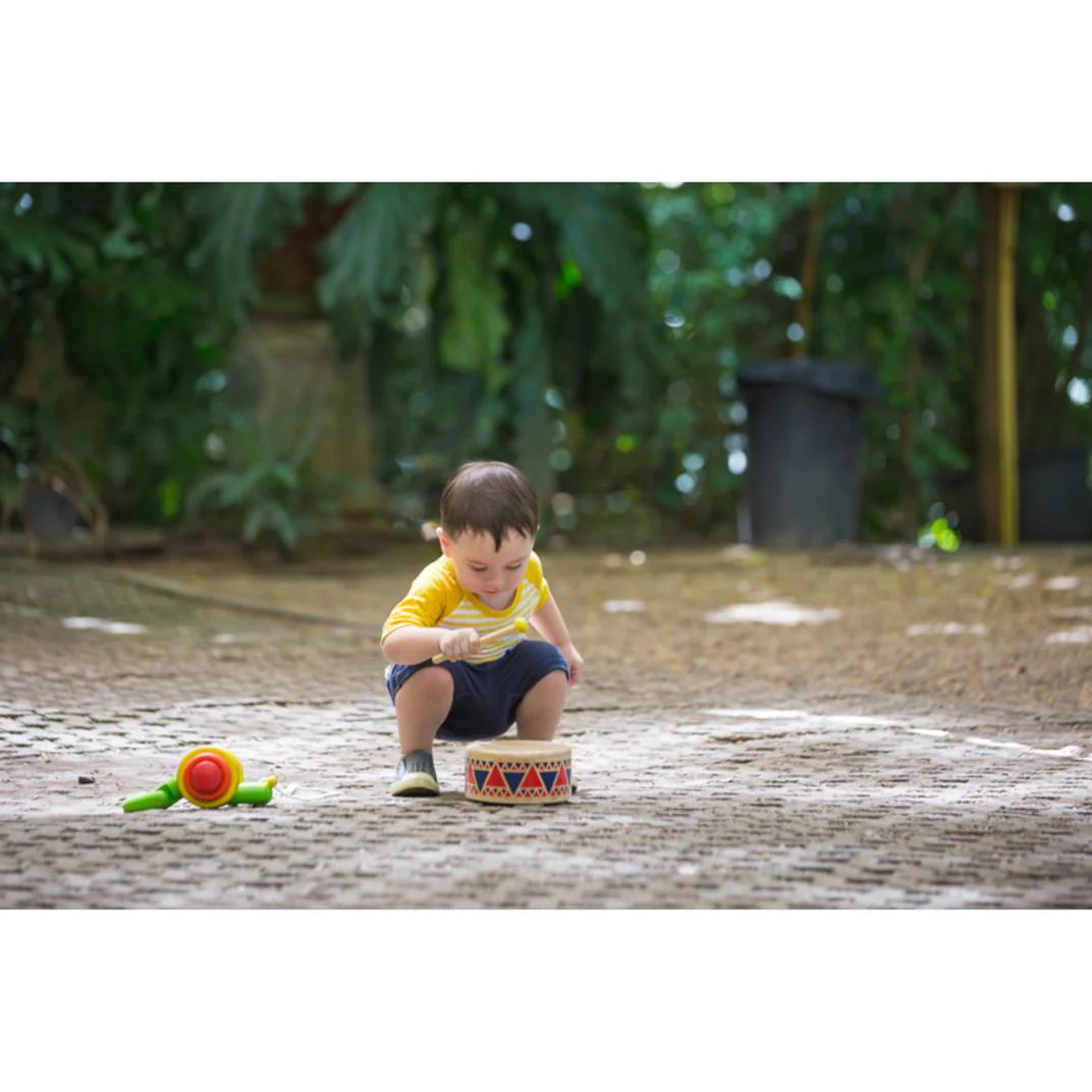 Little boy plays a Toy Wooden Drum from PlanToys made from solid wood