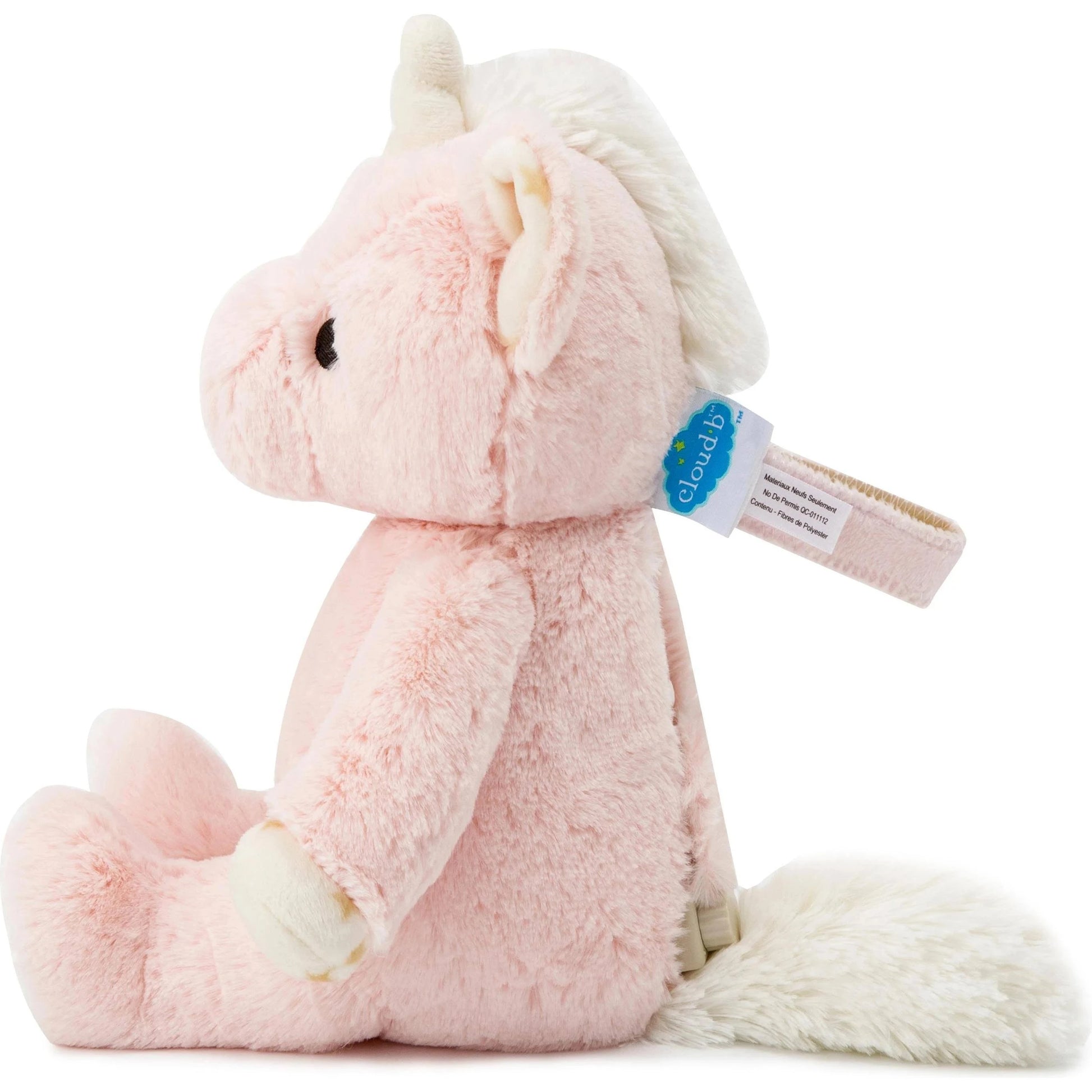 A plush Ella the Unicorn toy in soft pink with a fluffy cream-colored horn shows the velcro strap that attaches the sound machine to a crib or stroller. 