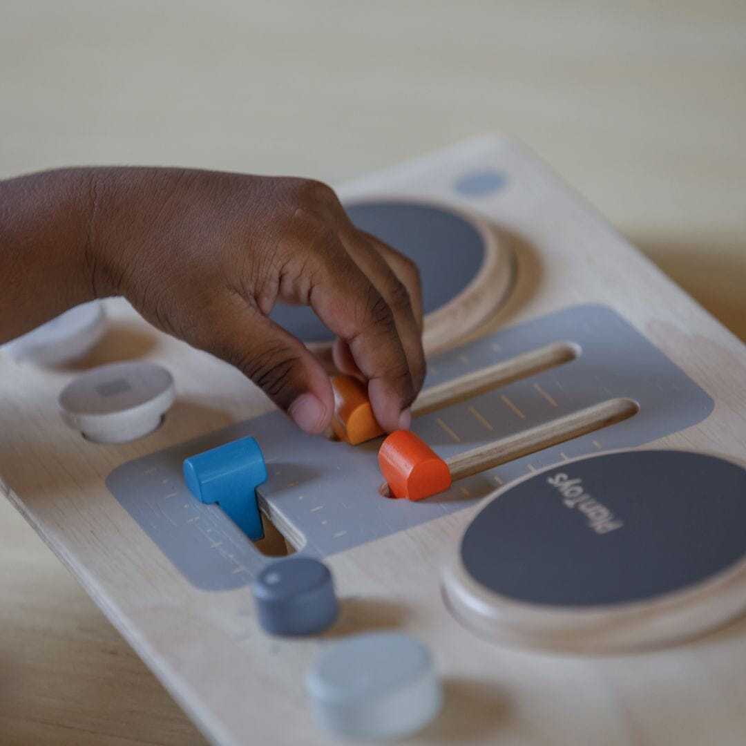 Child moves knobs on Plan Toys DJ Mixer Board 