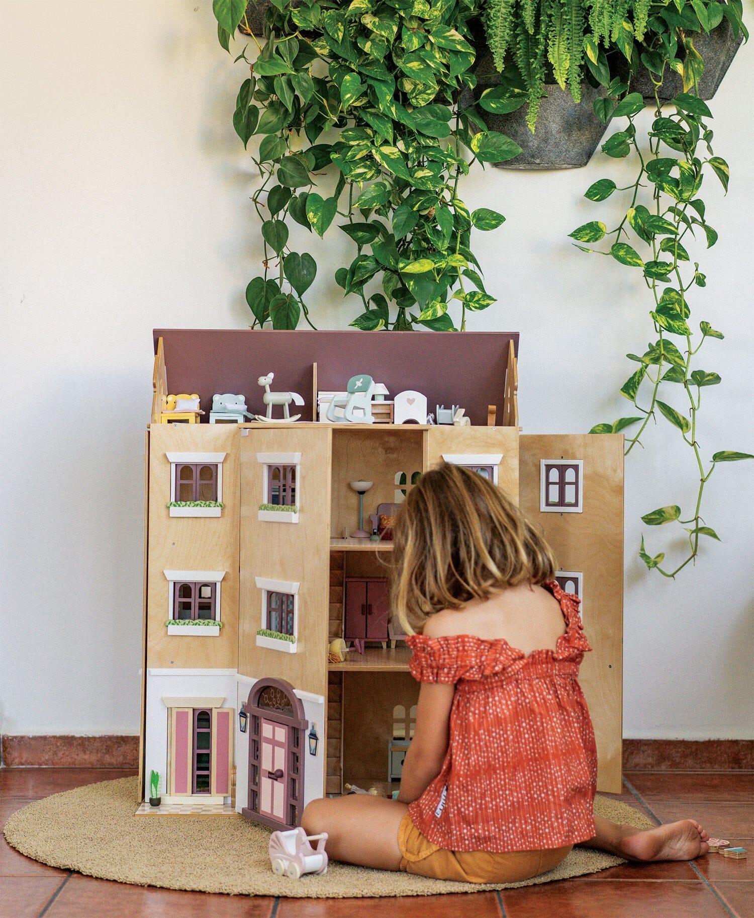 Child plays with the 3 story dollhouse Fantail Hall by Tender Leaf Toys