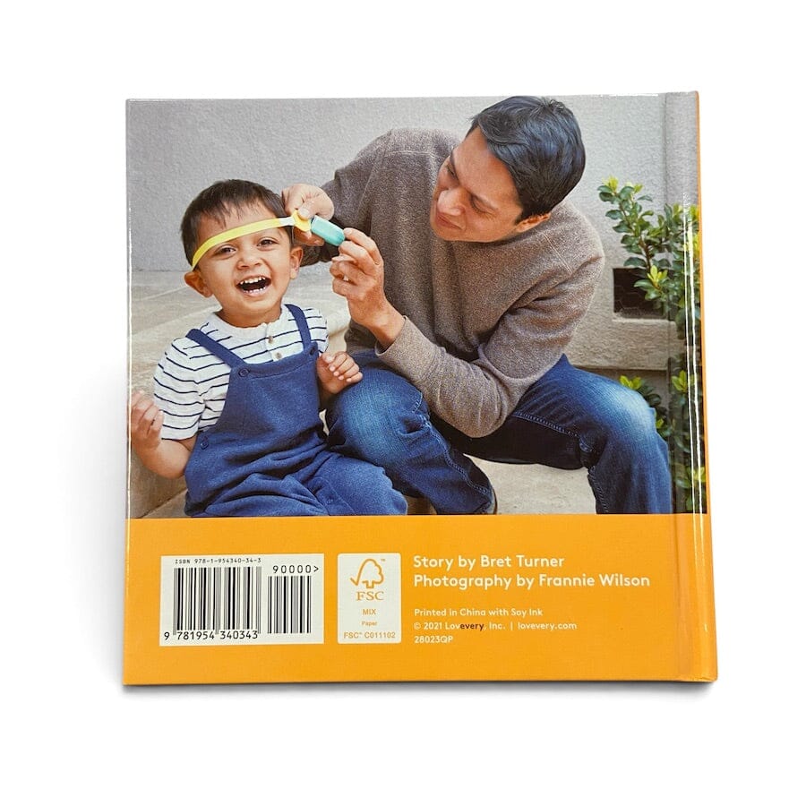 Measurement Day board book photographed from the back, featuring a large family photograph of an adult and child on the upper portion and an orange band with barcode, ISBN, and publication credits along the bottom.