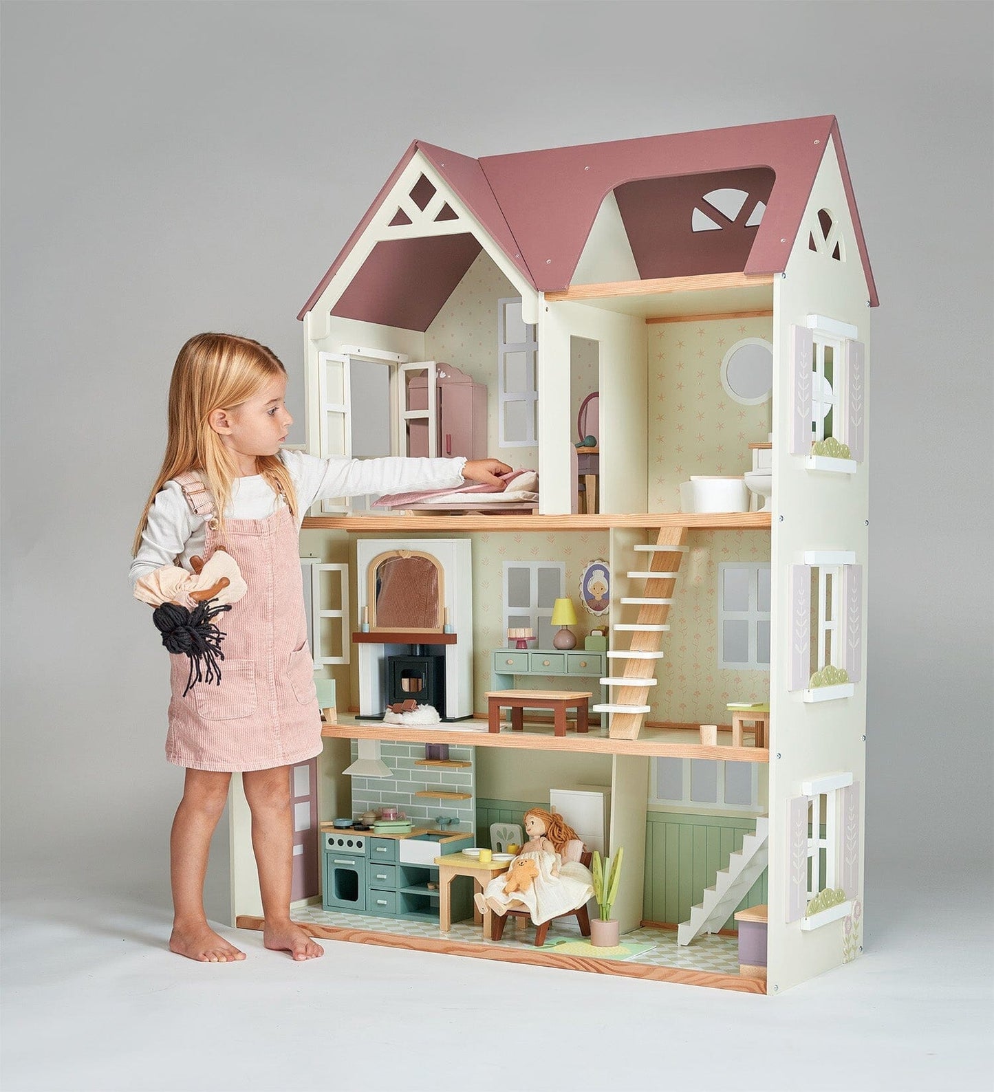 Child stands in front of Wood dollhouse with furniture Tender Leaf Mulberry Mansion 