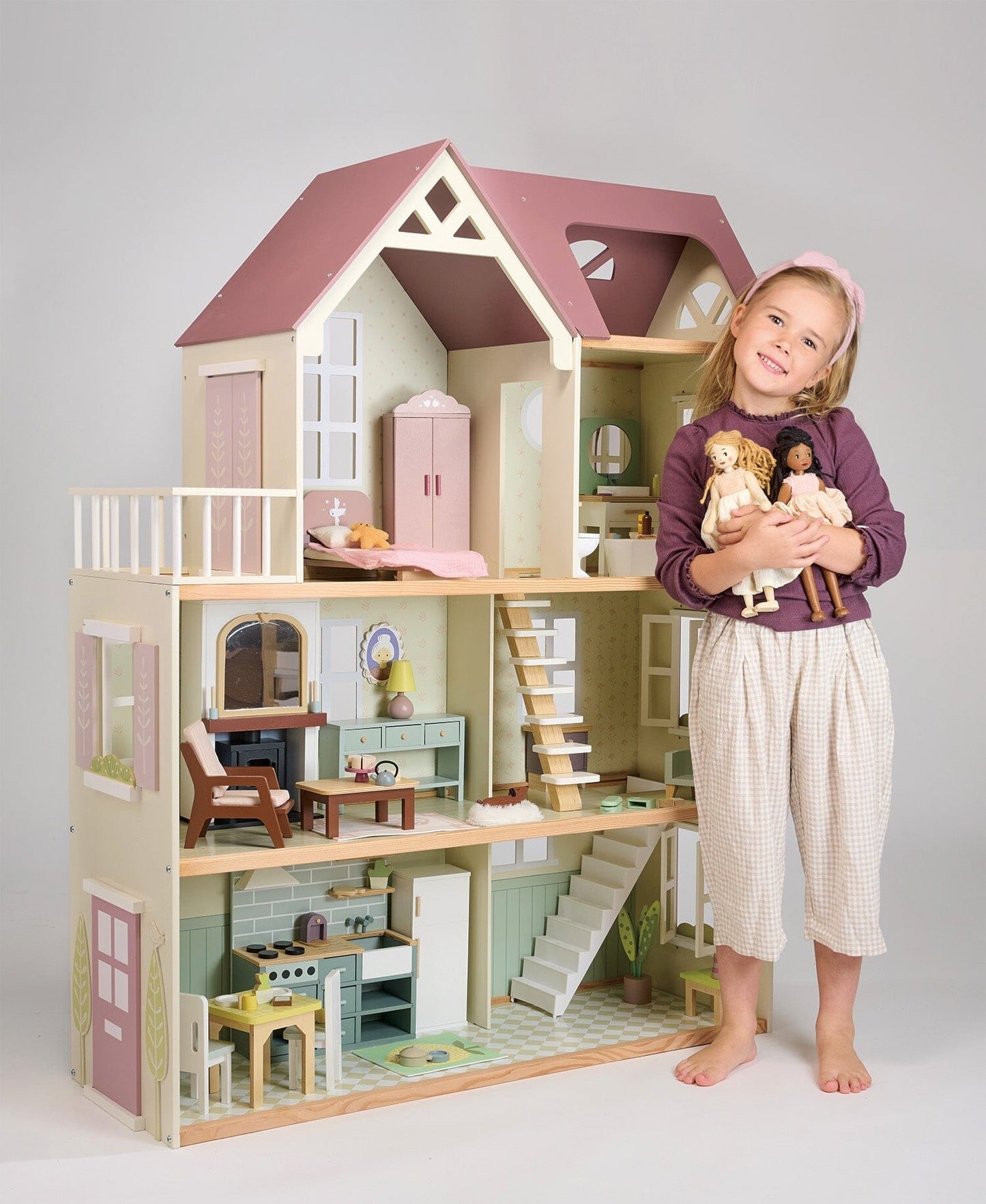 Child holds dolls from Wood dollhouse with furniture Tender Leaf Mulberry Mansion 