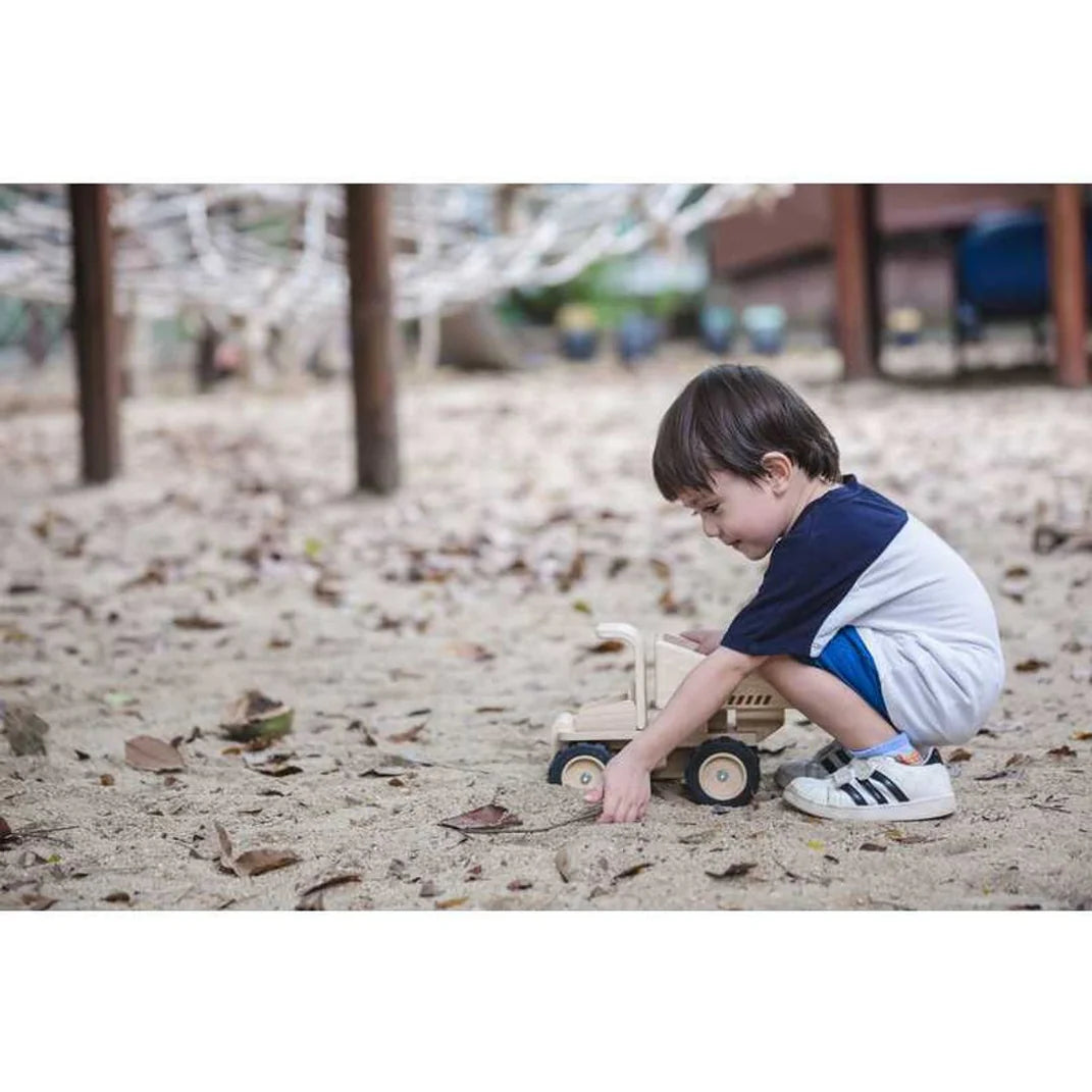 PlanToys Dump Truck Toys  - boy plays with toy wooden truck in sand