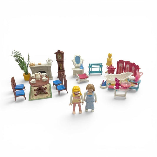 A Playmobil miniature dollhouse-style living room set with two small toy figures, including furniture such as chairs, a table, fireplace, mirror, bathtub, and decor, photographed on a plain white background.