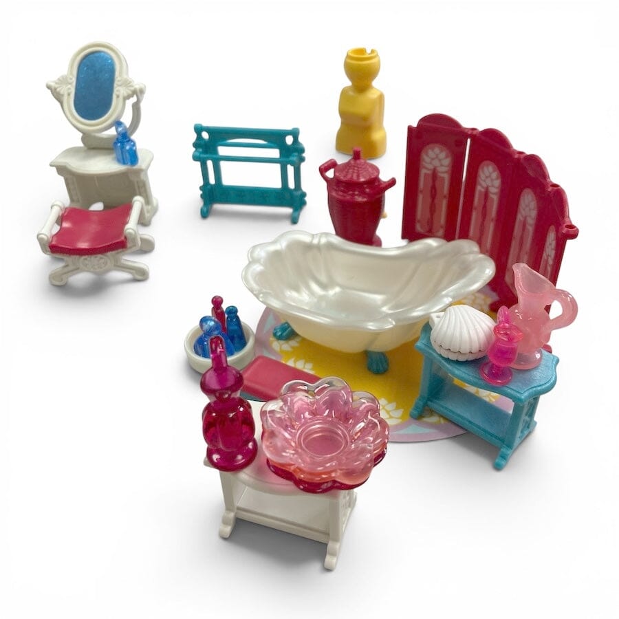 A Playmobil miniature dollhouse-style bathroom set with a white clawfoot bathtub, red vanity, pink flower-shaped bowl, turquoise shelf, yellow stool, and assorted small accessories on a white background.