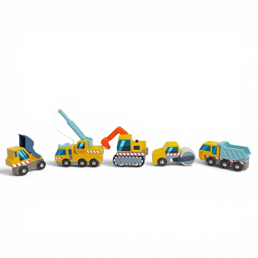 A set of 5 Tender Leaf Wooden Construction Vehicles in yellow and blue lined up in a row including a dump truck, front loader, excavation digger, crane truck, road roller against a white background.