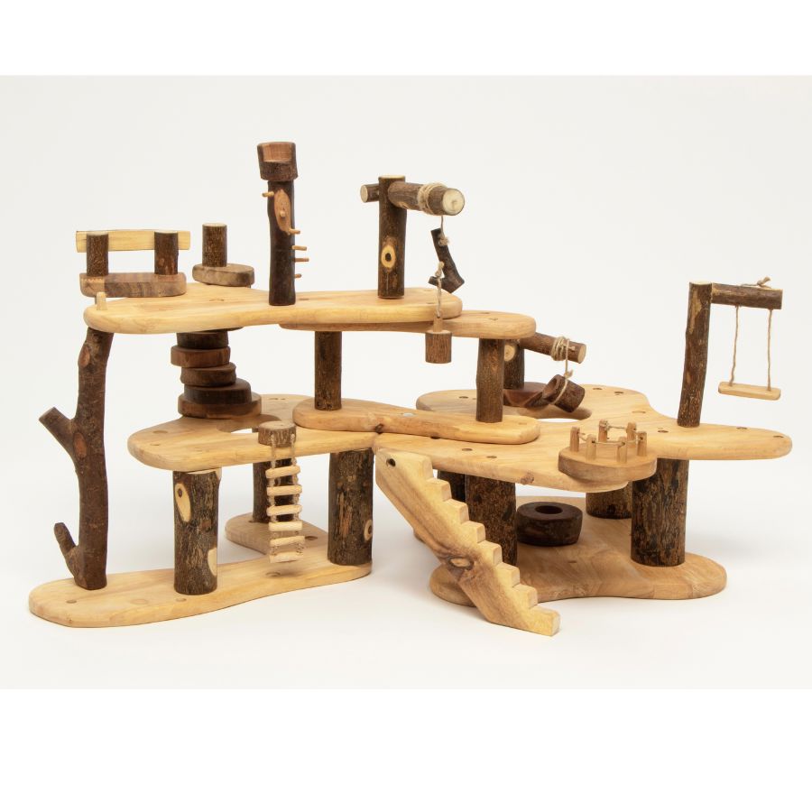 A Tree Blocks Build a Treehouse play structure made from natural logs and light wood boards, featuring platforms, stairs, hanging ropes, and small wooden toys, photographed on a clean white background.