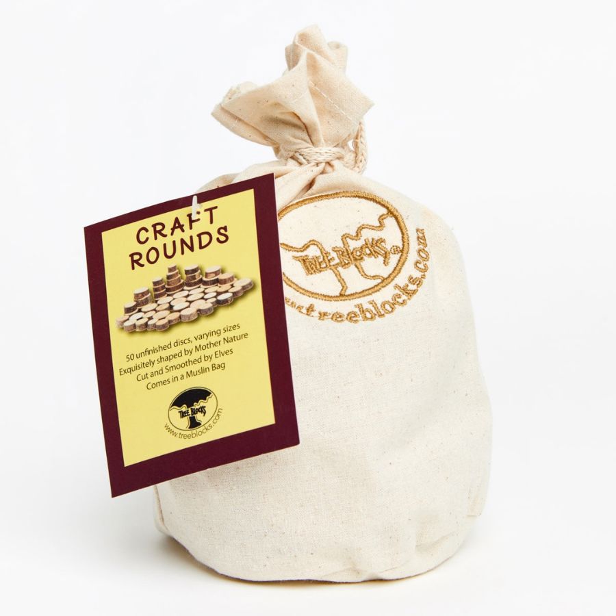 An off-white canvas drawstring bag with a gold-embroidered logo, featuring a yellow and burgundy paper tag that reads 'CRAFT ROUNDS' and shows a photo of wooden craft discs.