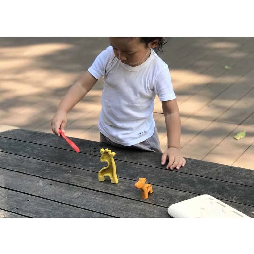 Boy plays with giraffe wooden puzzle pieces from the PlanToys Giraffe Puzzle & Play Set Toys 