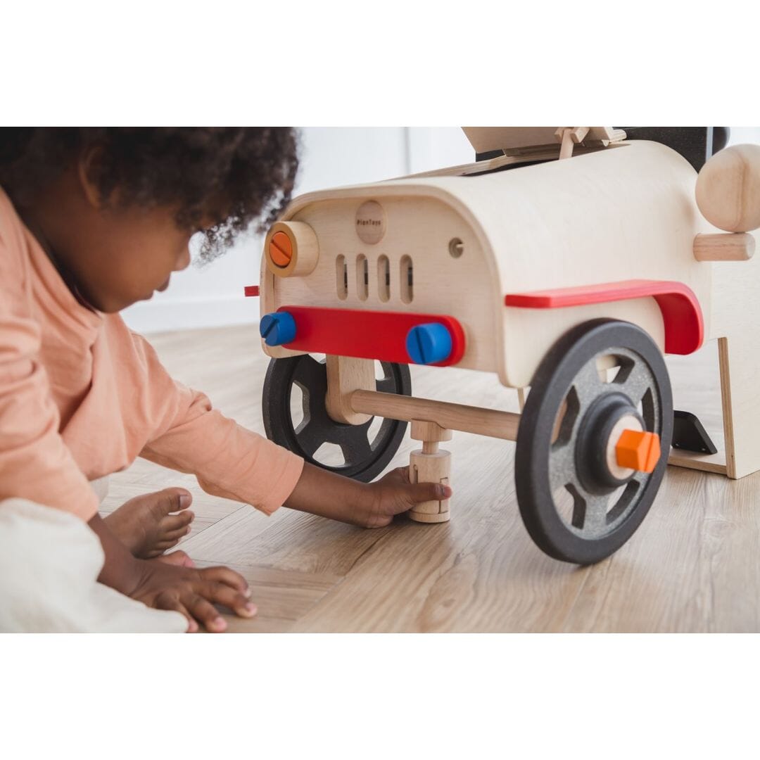 Child plays with PlanToys Motor Mechanic car for 3 year olds and up