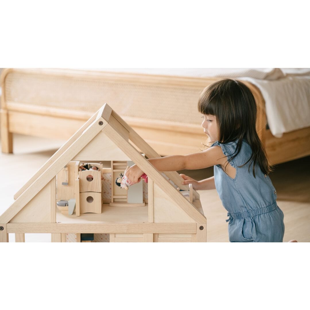 Child plays with PlanToys My First Wooden Dollhouse with A-frame and open floor plan allowing child to easily reach inside. 