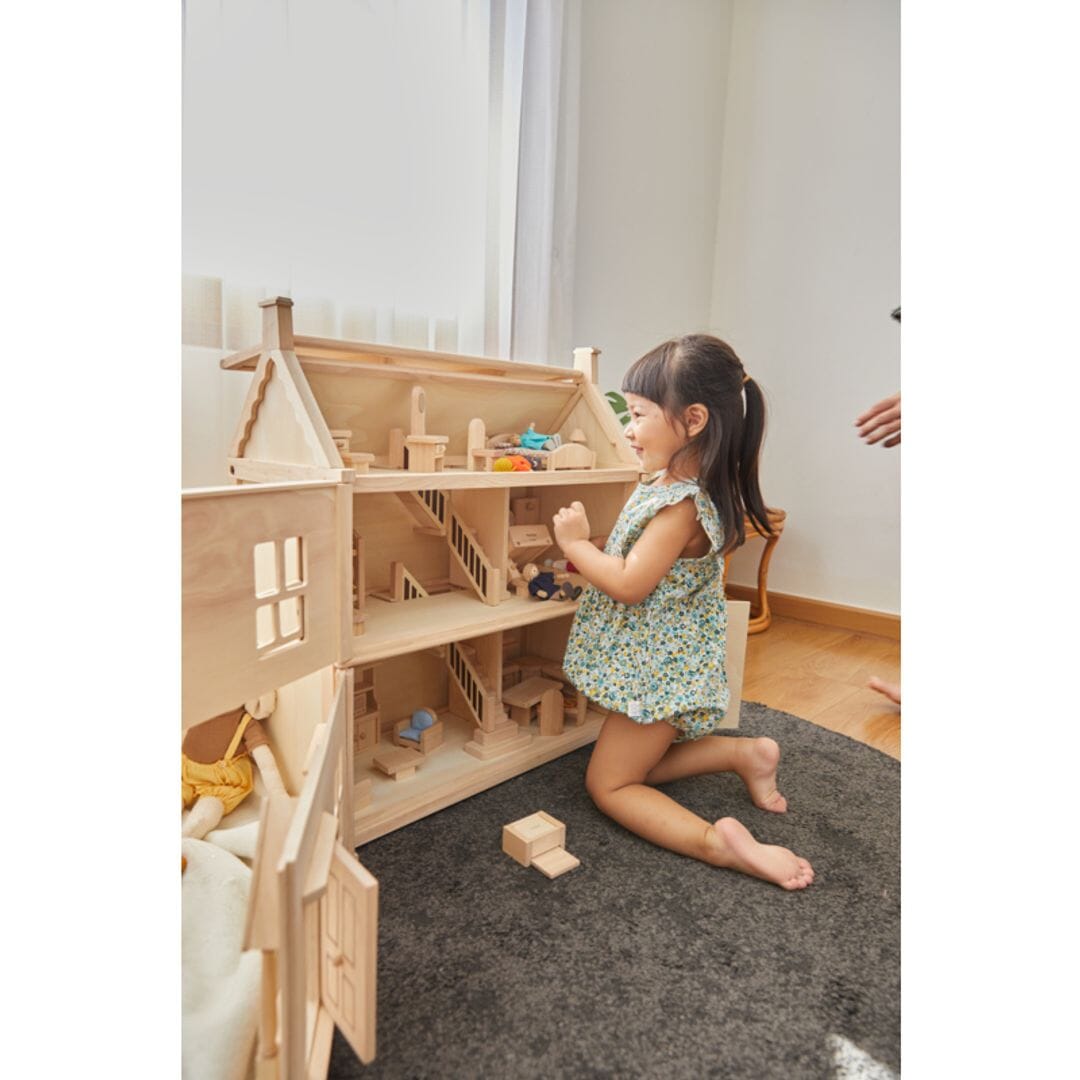 Child plays with PlanToys Victorian Dollhouse natural wooden dollhouse with 3 stories including attic - natural finish.