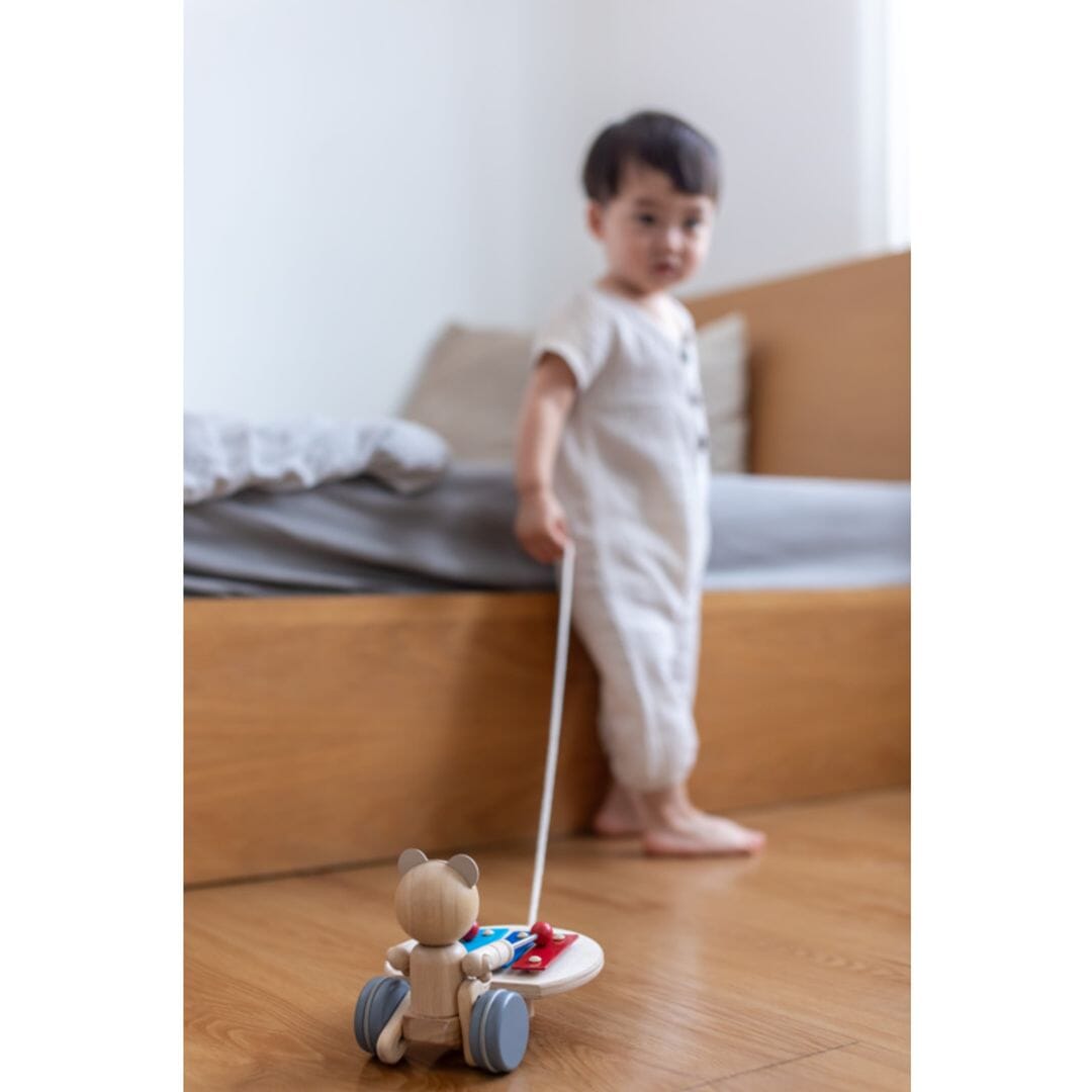 Toddler plays with PlanToys Pull Along Musical Bear